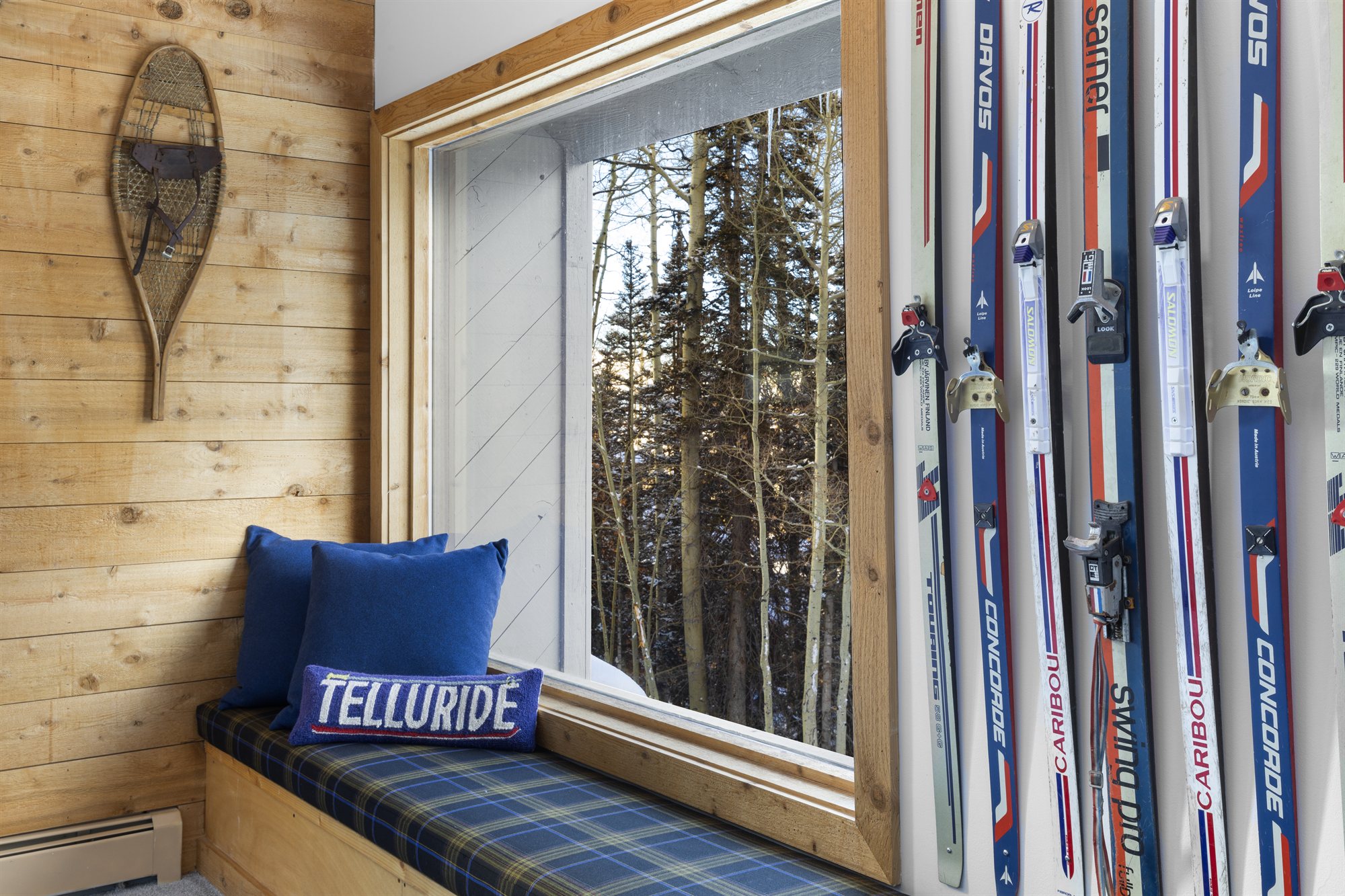 Bunkroom with white bunk beds, vintage skis, and a window seat