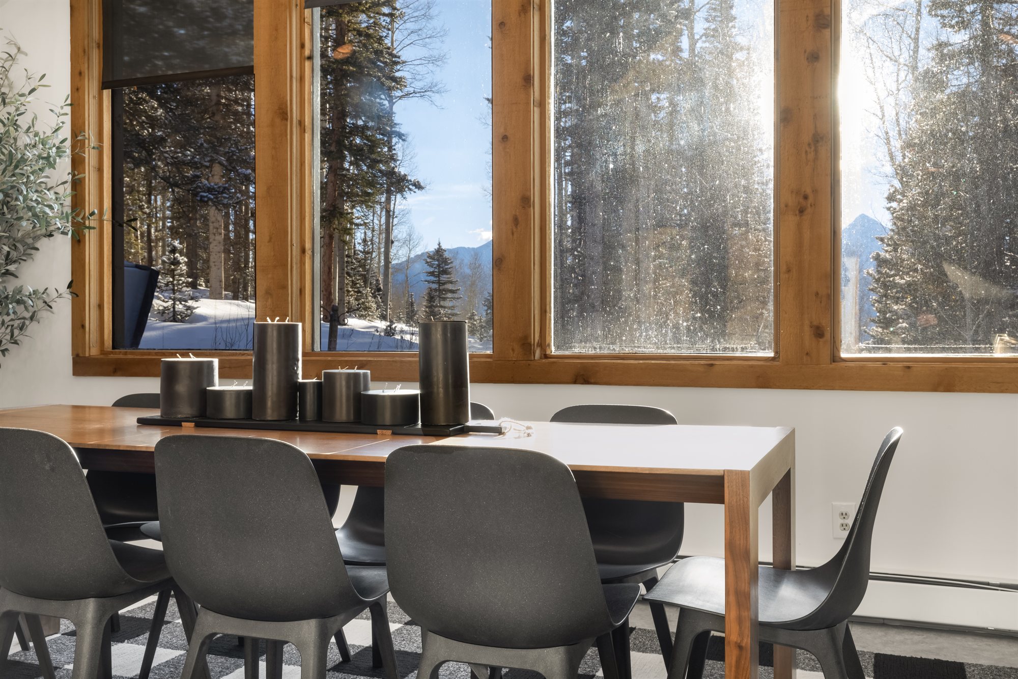 Dining table beneath tall windows over the snowy forest