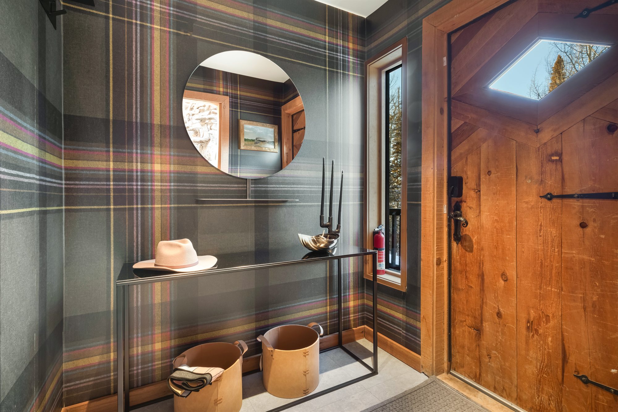 Entryway with plaid wallpaper and round mirror