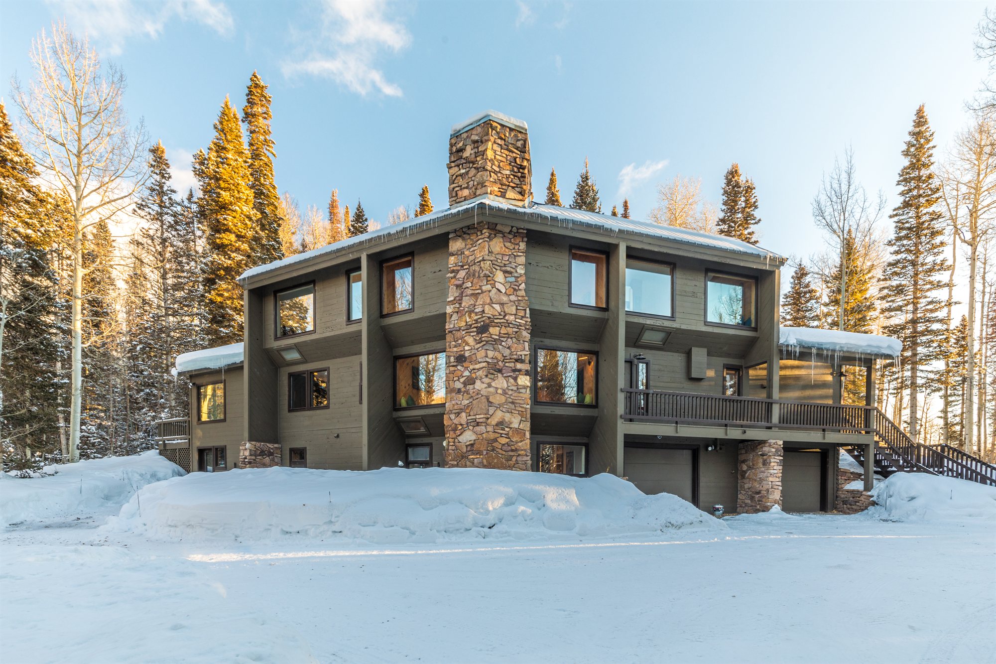 Black Bear Lodge in winter, windows lit, framed by snow and golden aspens