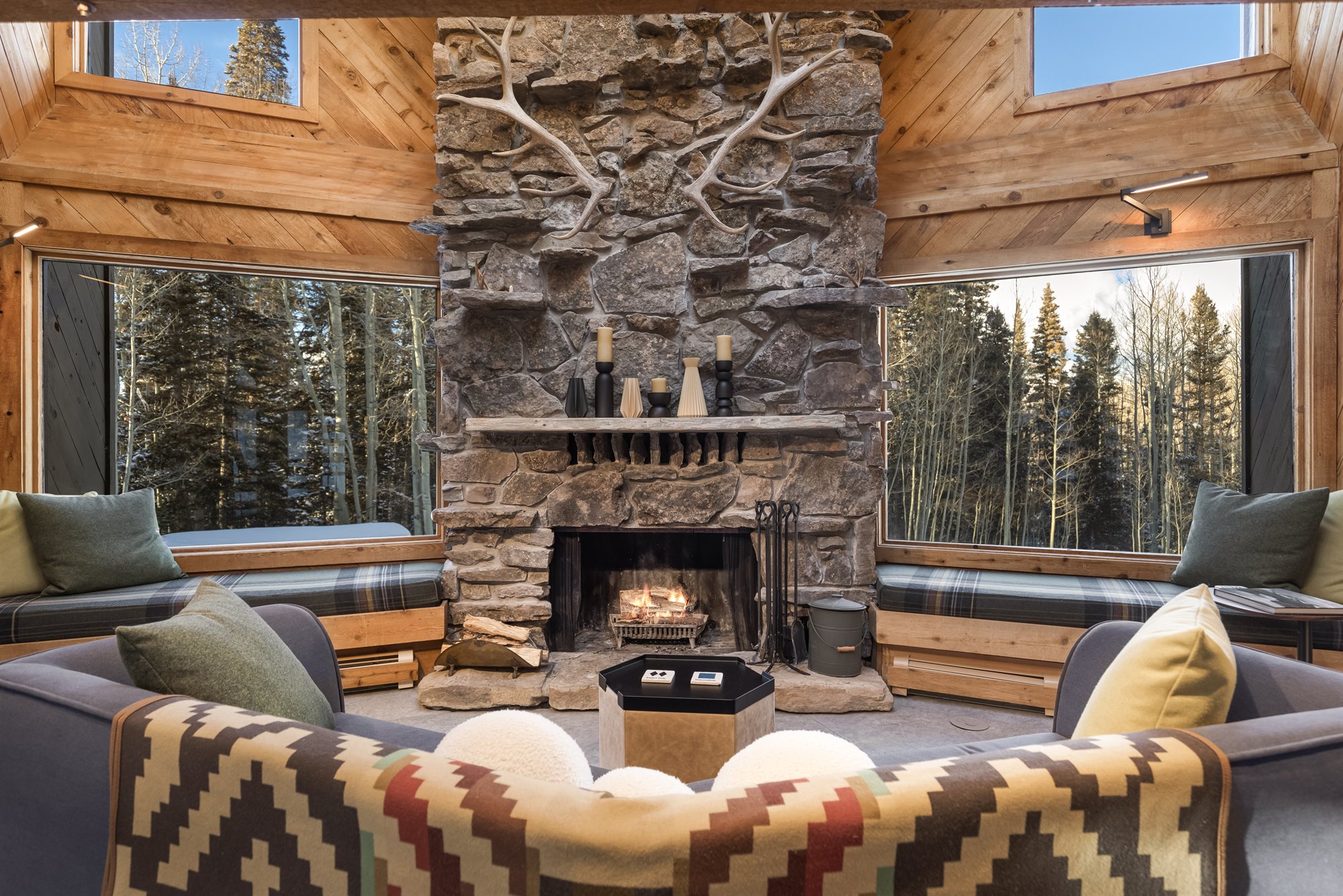 The living room stone fireplace with antlers mounted above the mantel and cushioned window seats on either side