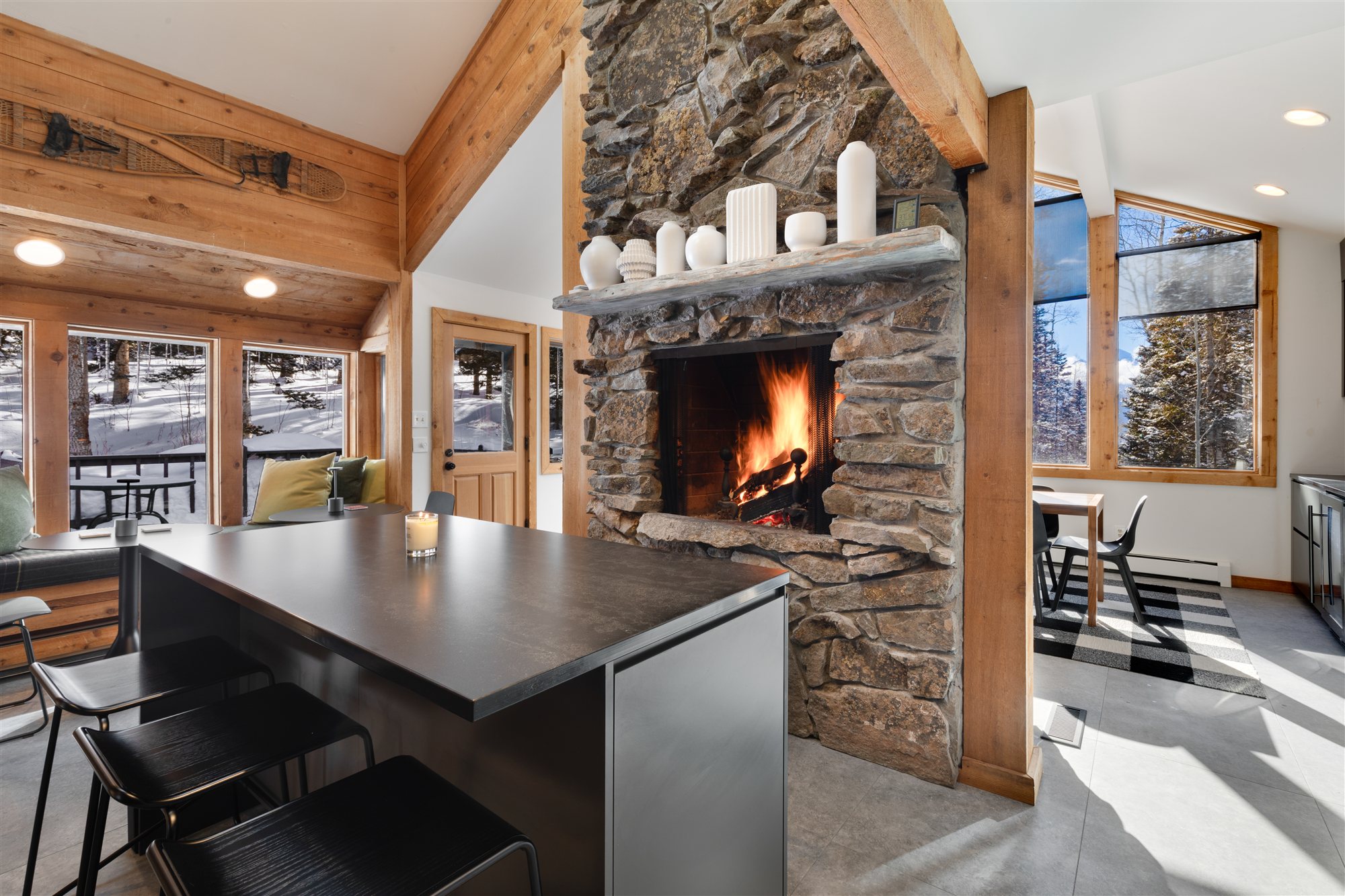 The kitchen island facing the stone hearth, fire lit and candles on the mantel