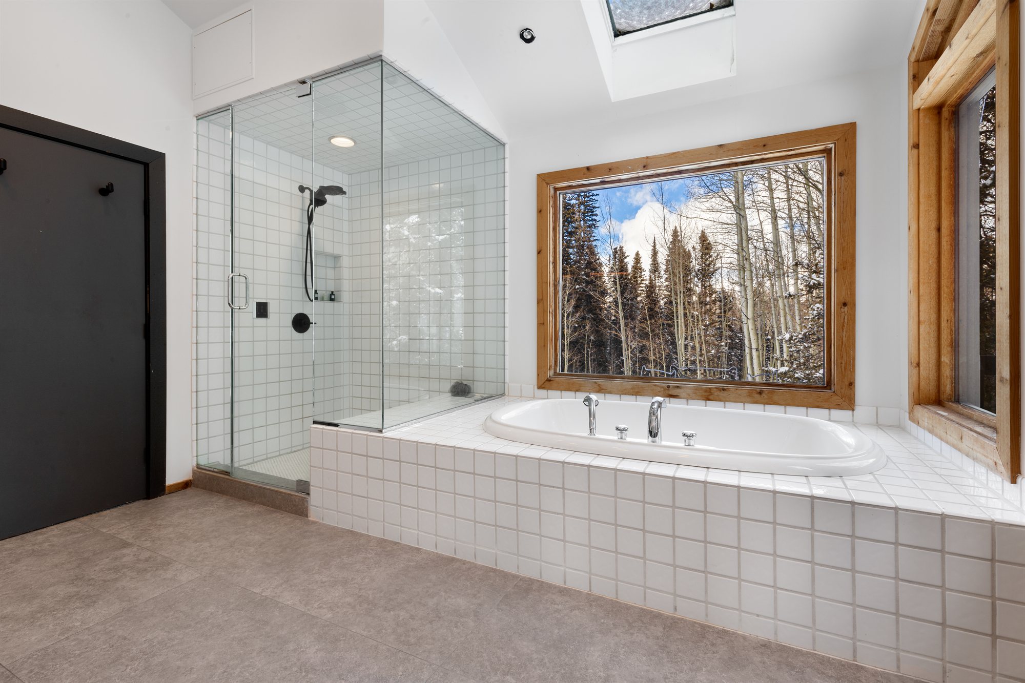 Soaking tub beneath a forest-view window