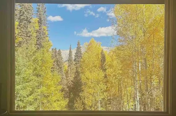 Golden aspens and a distant peak framed by a lodge window